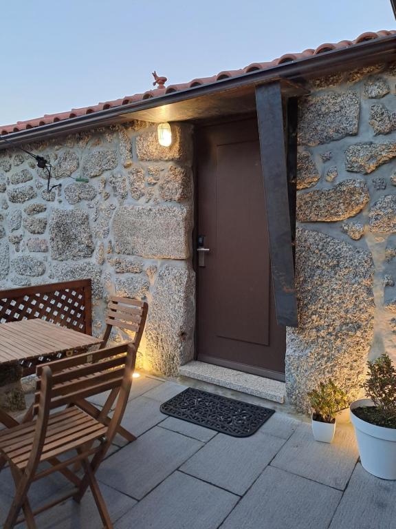 a patio with a wooden door and a table and chairs at VillaGarcia-Casa da Peneira in Terras de Bouro