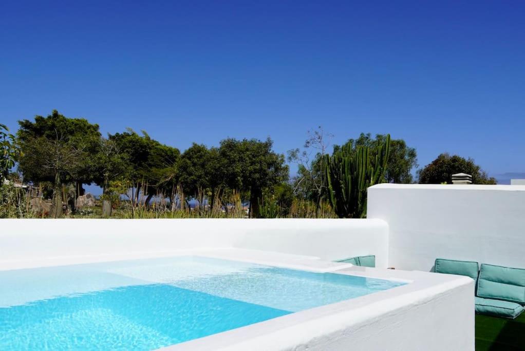 una piscina con 2 sillas junto a una pared blanca en Casa Notas de Color Y Sal, en Agaete