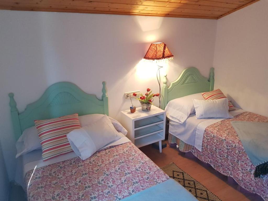 a bedroom with two beds and a table with a lamp at Adro Redondela in Redondela