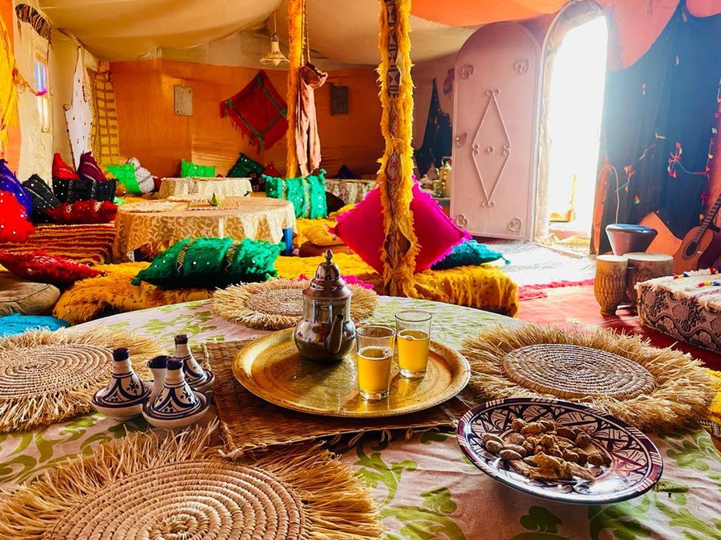 ein Zimmer mit einem Tisch mit Speisen und Getränken darauf in der Unterkunft Authentique berber Camp in M’hamid El Ghizlane