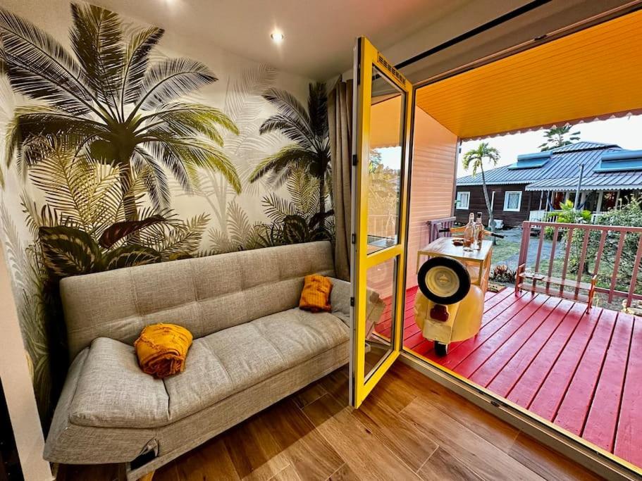 ein Wohnzimmer mit einem Sofa auf einer Veranda in der Unterkunft Ti Kaz Coco JUNGLE Jacuzzi & vue mer in Bouillante