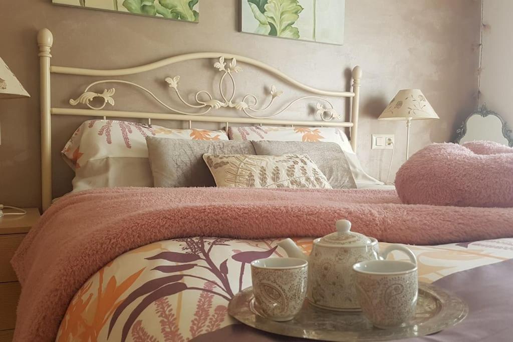 łóżko z różowym kocem i dwie filiżanki na tacy w obiekcie Casa Maite w mieście Palamós