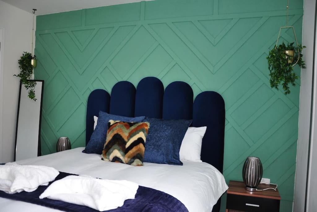 a bed with a blue headboard and a green wall at Stunning 2 bedroom apt in Milton Keynes
