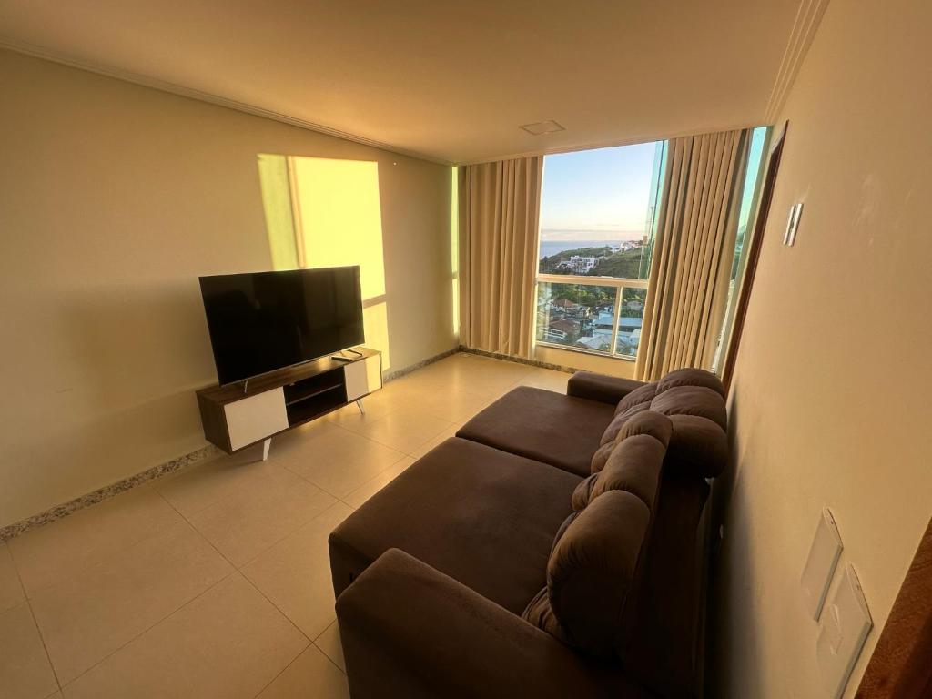 uma sala de estar com um sofá e uma televisão de ecrã plano em Apartamento Iriri Vista para o Mar em Iriri