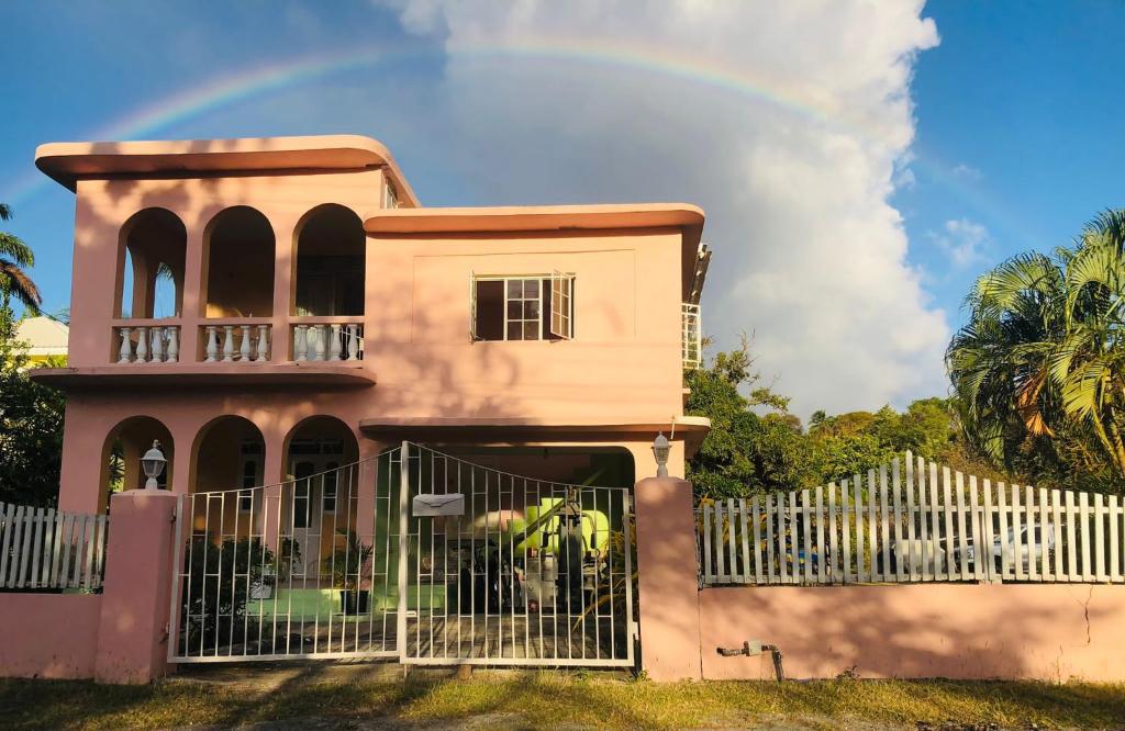 a rainbow over a house with a fence at Rain in Bridgetown