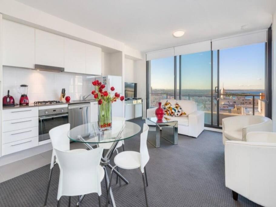 a kitchen with a glass table and white chairs at 806/67 Arvia in Newcastle