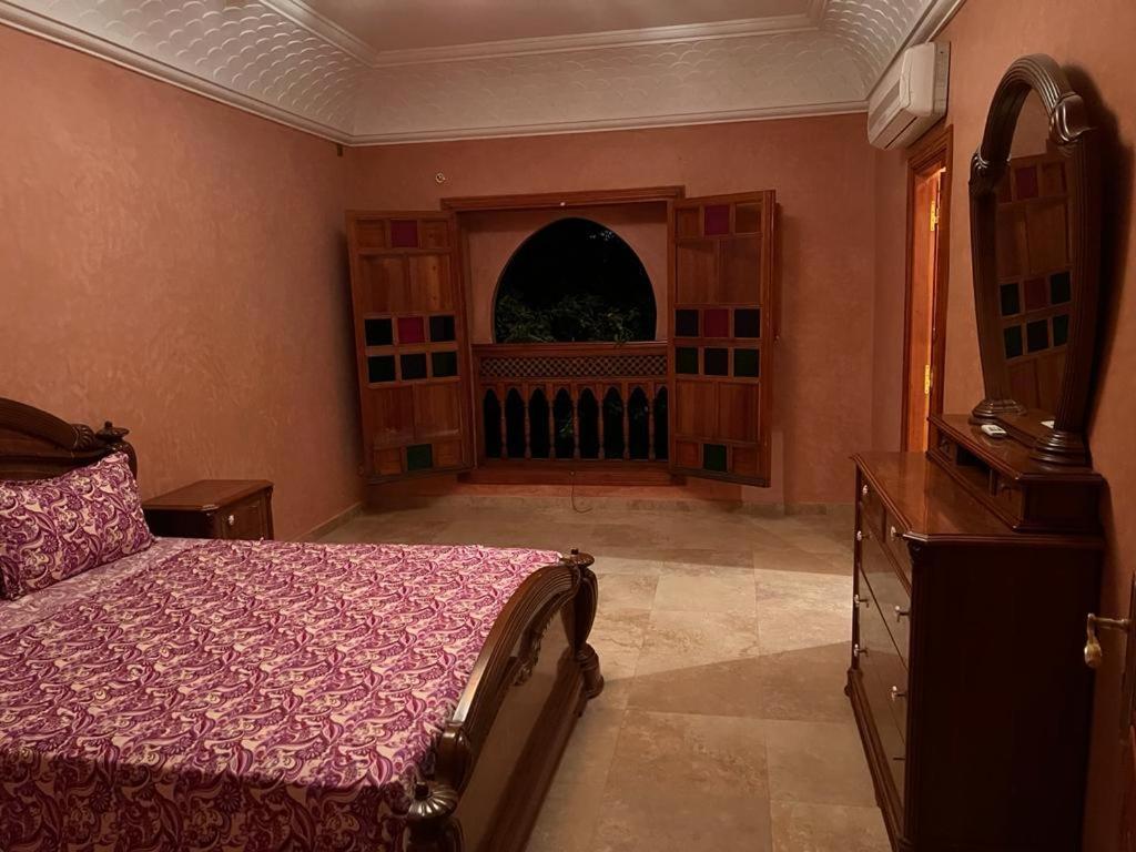 a bedroom with a bed and a dresser and a window at villa OUSSAMA in Marrakech