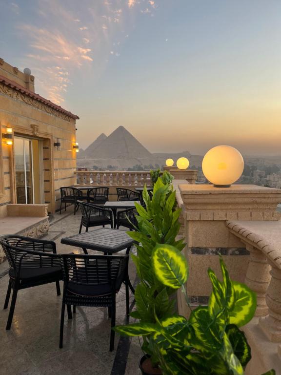 a patio with tables and chairs with a pyramid in the background at Crowne Pyramids view inn in Cairo