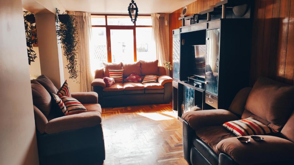 sala de estar con sofás de cuero y TV en FABRIZIO GUEST HOUSE en Cusco