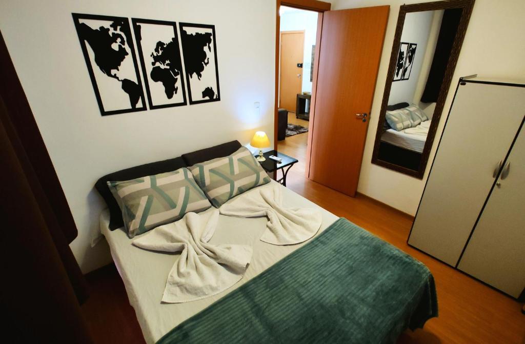 ein Schlafzimmer mit einem Bett in einem Zimmer mit einem Spiegel in der Unterkunft Apto Executivo Ravena in Campo Grande