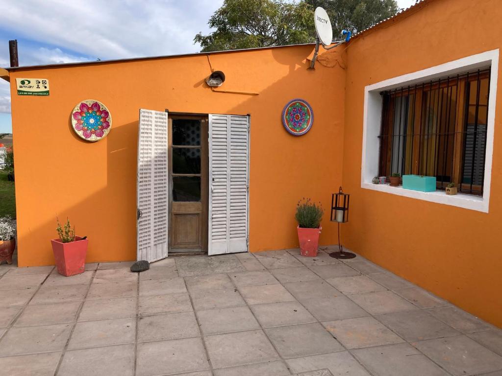 ein orangefarbenes Haus mit einer Tür und einer Terrasse in der Unterkunft Casa de campo rústica in Tandil