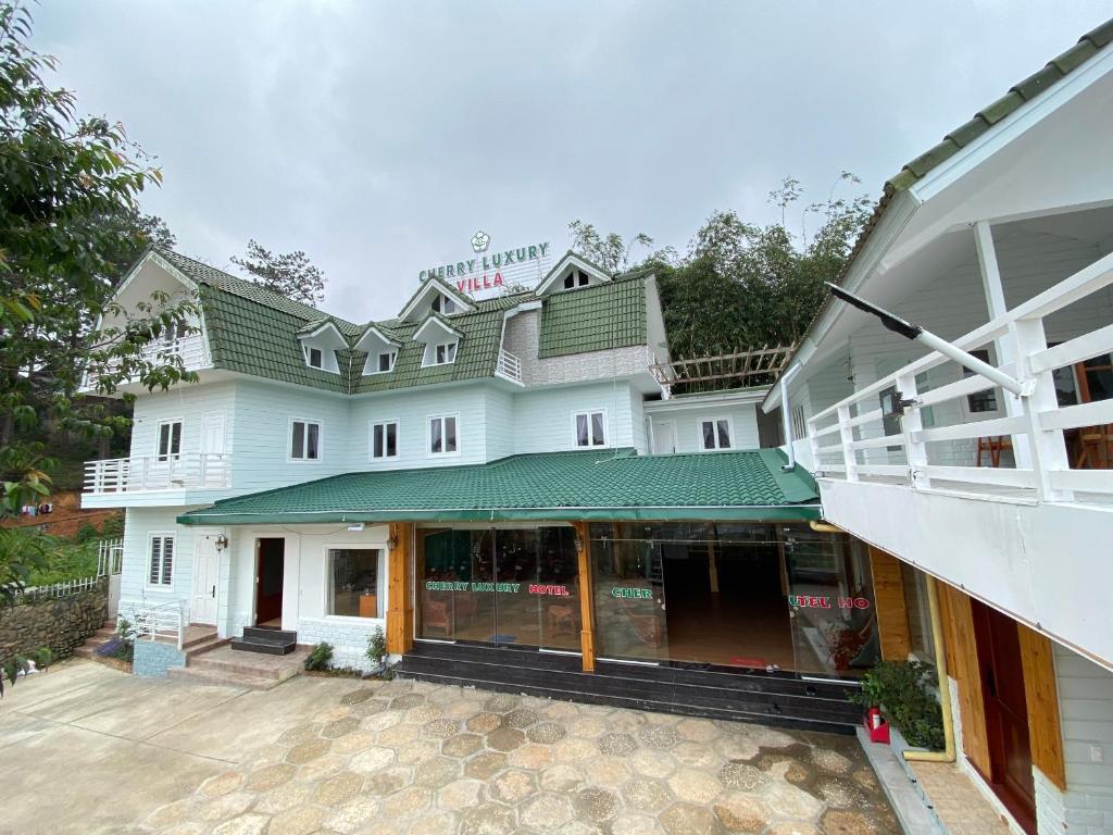 a large white building with a green roof at Cherry Luxury Hotel in Da Lat