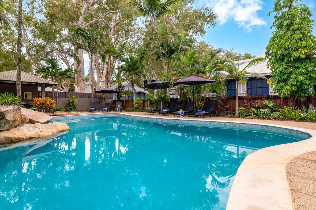 a swimming pool with blue water and trees at Paradise On The Beach Resort in Palm Cove