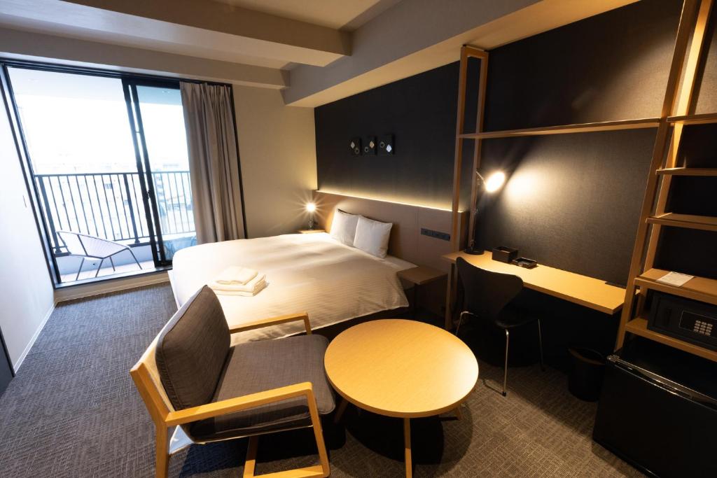 um quarto de hotel com uma cama, uma secretária e uma mesa em N Plus Hotel Akihabara em Tóquio