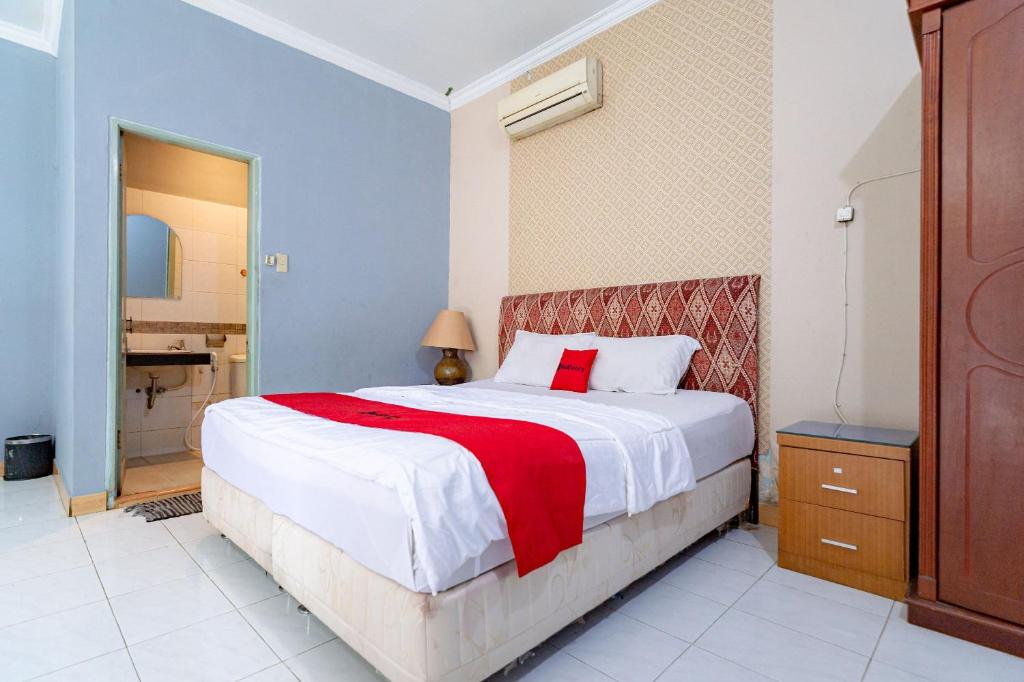 a bedroom with a large bed with a red blanket at RedDoorz Plus @ Jalan Iskandar Muda Medan in Medan