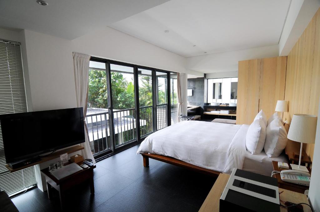 a bedroom with a bed and a television and a balcony at Fu Wan Cafe Villa in Donggang