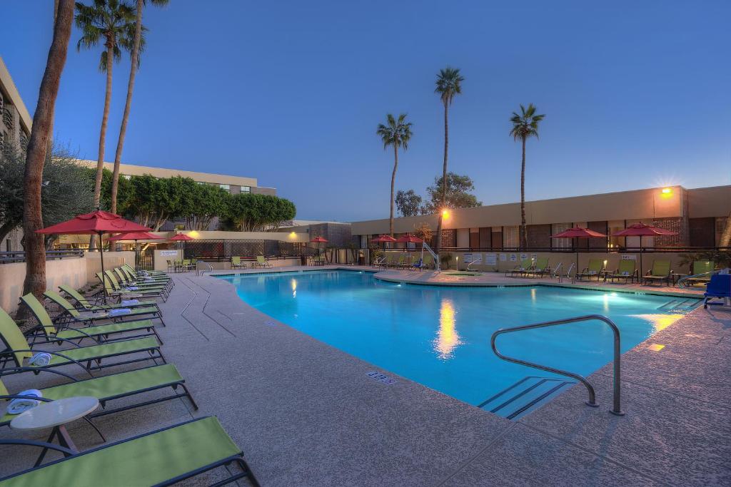 a large swimming pool with lounge chairs and palm trees at DoubleTree by Hilton Phoenix North in Phoenix