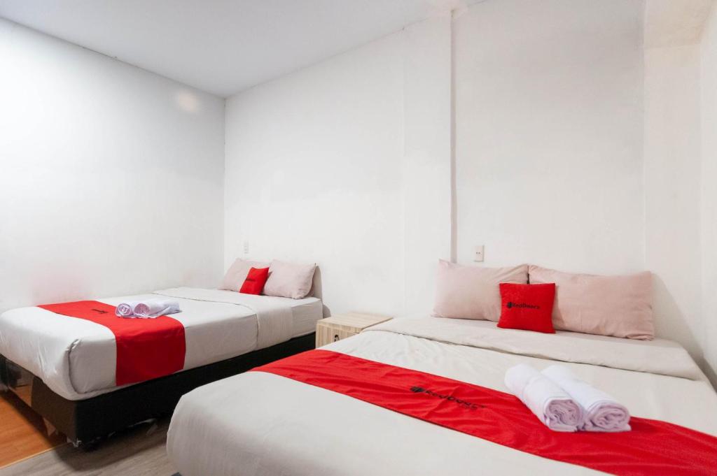 - une chambre avec 2 lits dotés de draps rouges et blancs dans l'établissement RedDoorz At Jalan Asia Medan, à Medan