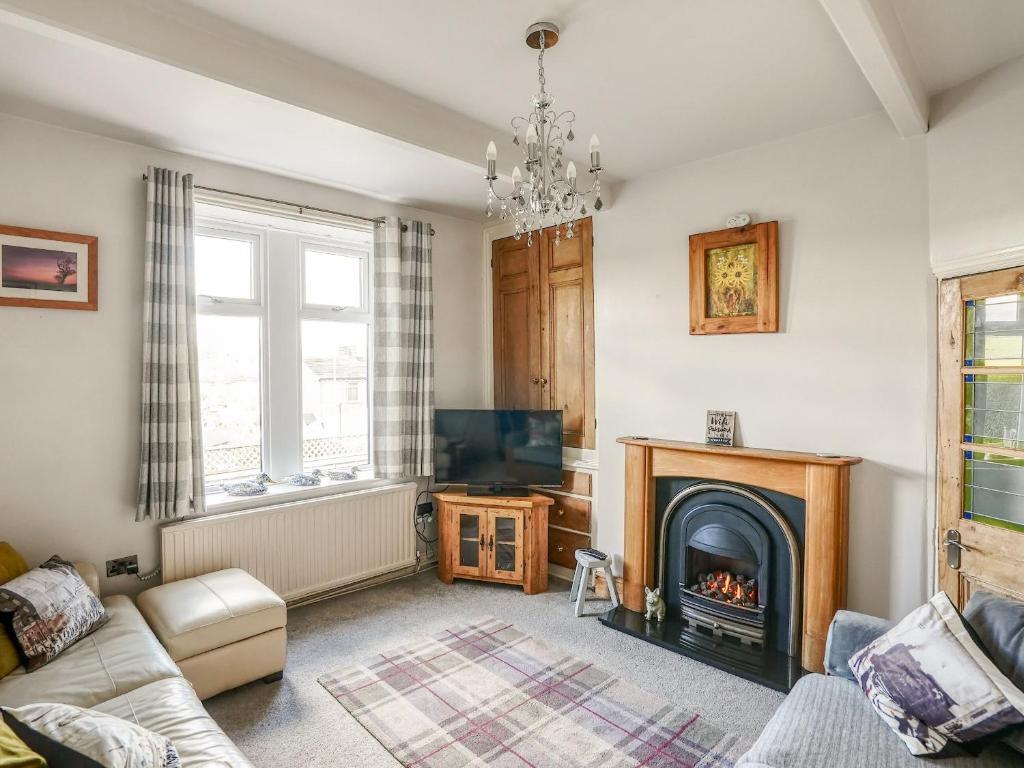 a living room with a fireplace and a couch at Strawberry Cottage in Haworth