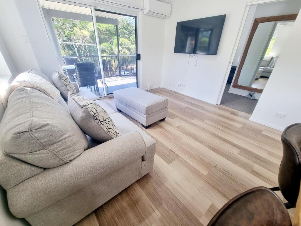 a living room with a couch and wooden floors at Stunning 2 BR, 2 Bathroom Beachfront Apartment Close To Everything! in Hervey Bay