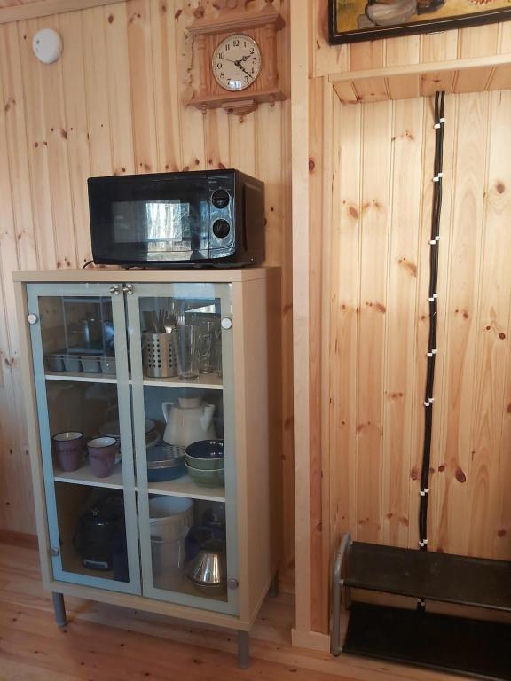 a cabinet with a microwave and a clock on a wall at Countrycabin Bergslagen stuga in Ramsberg