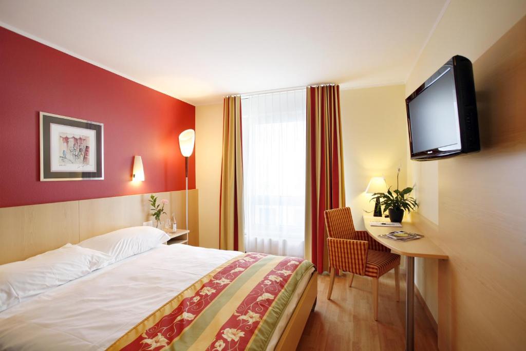 ルツェルンにあるAmbassador Self Check-in Hotelのベッド1台、薄型テレビが備わるホテルルームです。