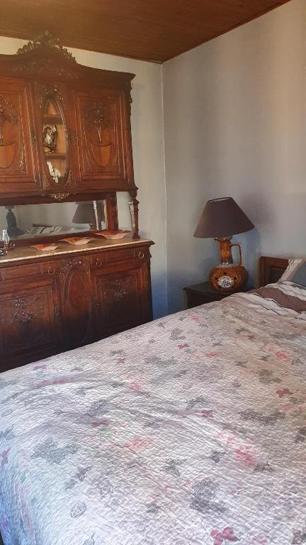 a bedroom with a large bed with a dresser and a lamp at Chateau Mano in Mairé-lʼEveseault