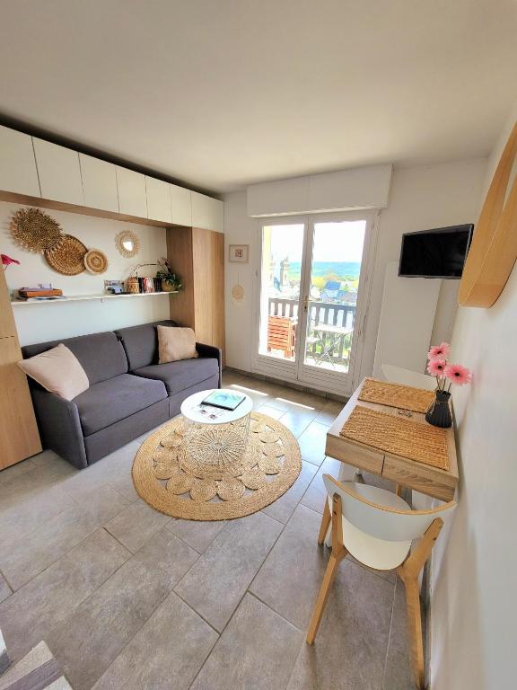 un salon avec un canapé et une table dans l'établissement M2M Studio magnifique vue mer - avec balcon - les pieds dans l eau!, à Blonville-sur-Mer