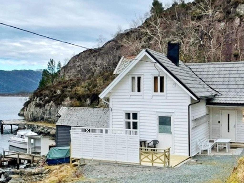 a white house next to a body of water at Three-Bedroom Holiday home in Svelgen in Sørgulen