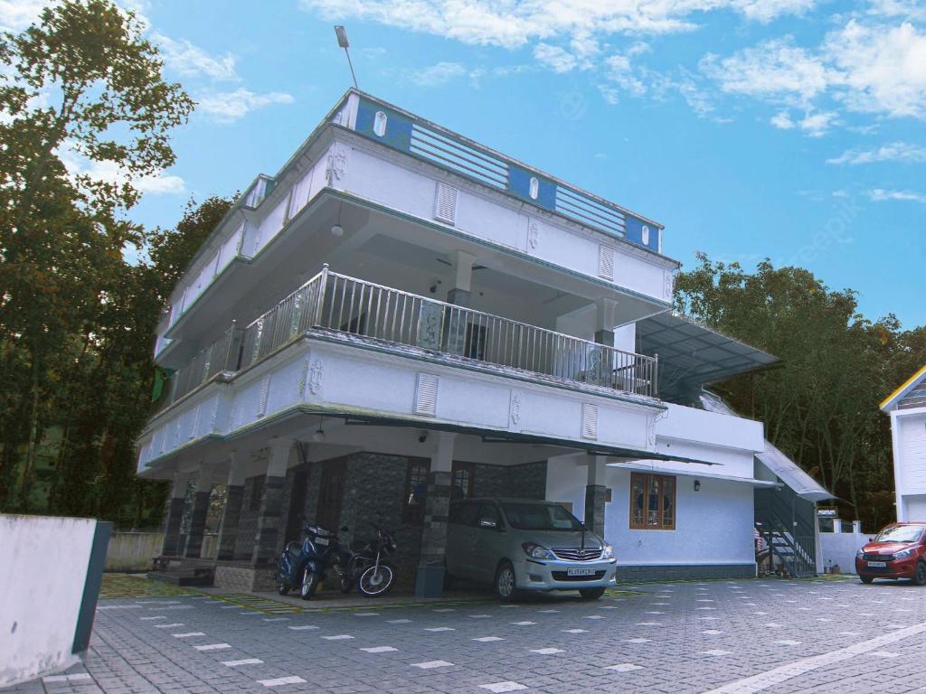Natureland Homestay في كوتايم: مبنى أبيض مع سيارة متوقفة في موقف للسيارات