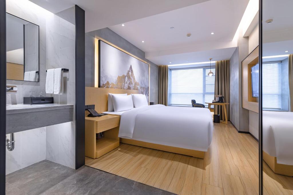 a hotel room with a white bed and a bathroom at Tuke China Hotel -Wenzhou South Bus Terminal in Wenzhou