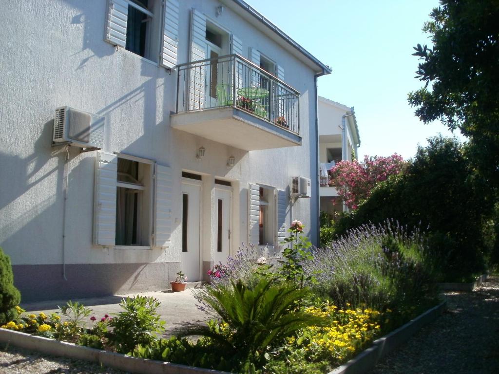 a white building with a balcony and flowers at Grgin Apartments in Kaštela