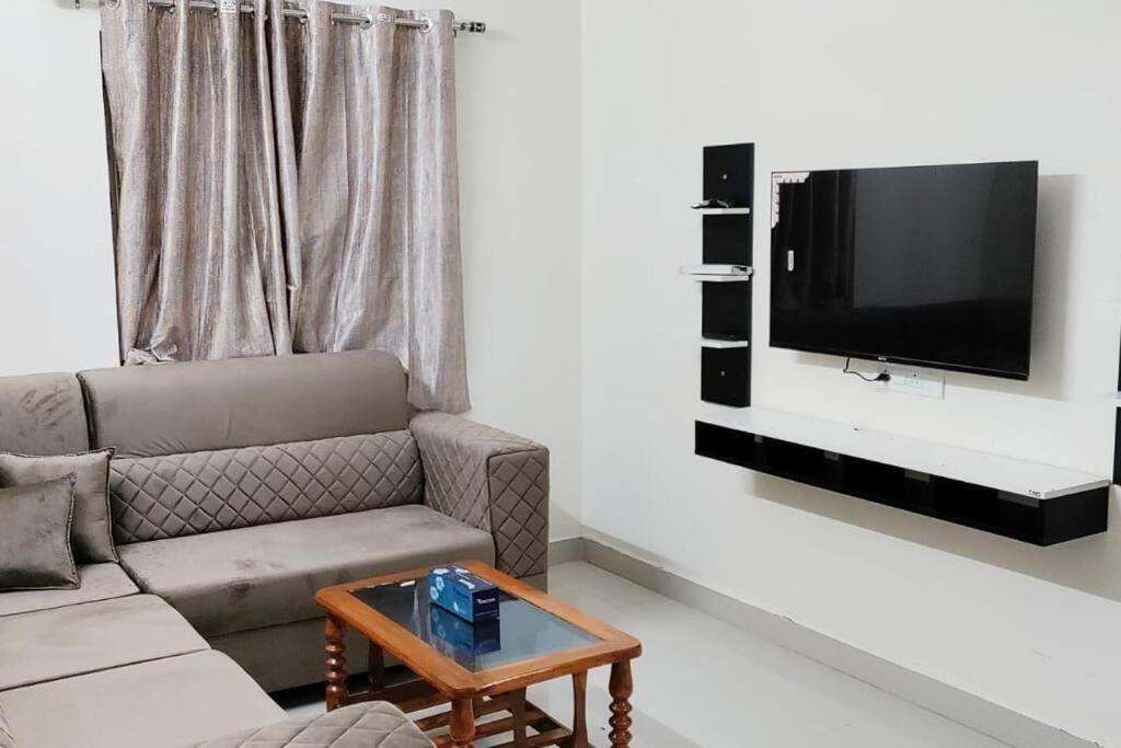 un soggiorno con un divano e una TV a parete di Servostay Fully Furnished 2 BHK in Hafeezpet #102 a Hyderabad