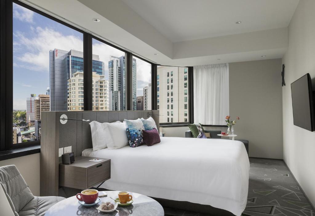 a bedroom with a large white bed and a large window at Capri by Fraser Brisbane in Brisbane