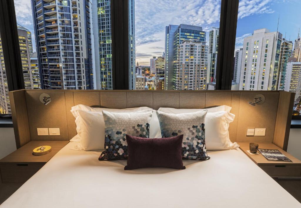 a bed in a room with a view of a city at Capri by Fraser Brisbane in Brisbane