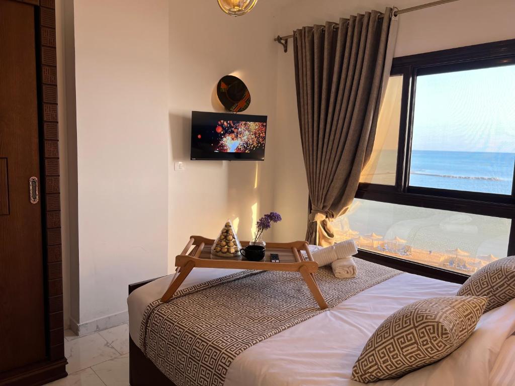 My Sky Sea View 1 Bedroom Apartment في الغردقة: غرفة نوم مع سرير مع طاولة عليه