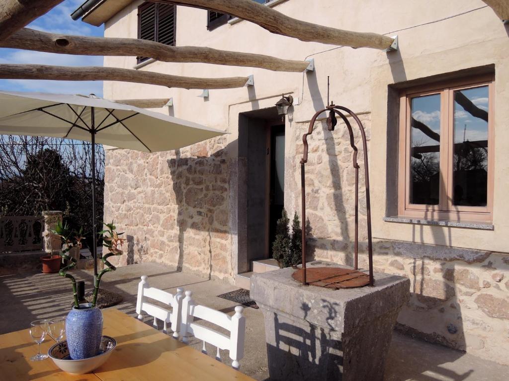 eine Terrasse mit einem Tisch mit einem Sonnenschirm und einem Tisch sidx sidx in der Unterkunft Apartment Pink Mimosa in Malinska