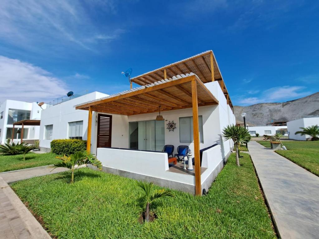 een wit huis met twee stoelen in de tuin bij Alquilo casa de playa Condominio Playa Azul cerca de Asia in Cerro Azul