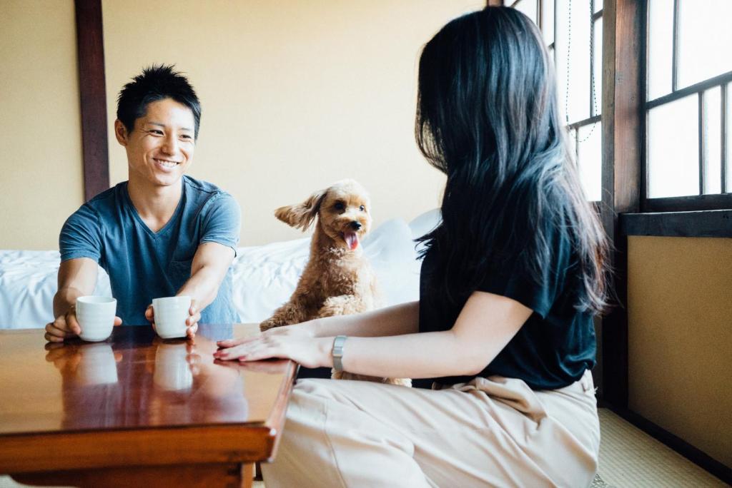 um homem e uma mulher sentados à mesa com um cão em Tenjin TABI-NE em Kanazawa