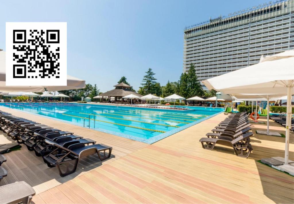 una gran piscina con sillas y sombrillas en Zhemchuzhina Grand Hotel, en Sochi
