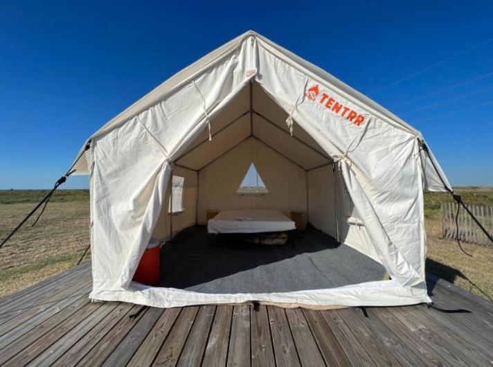 a tent with a bed in it on a wooden deck at Tentrr State Park Site - Texas Galveston Island- Beachside E - Single Camp in Galveston