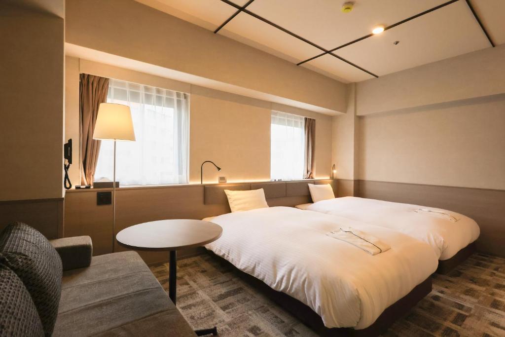 a hotel room with a large bed and a table at SK HOTEL Kobe Ekimae in Kobe