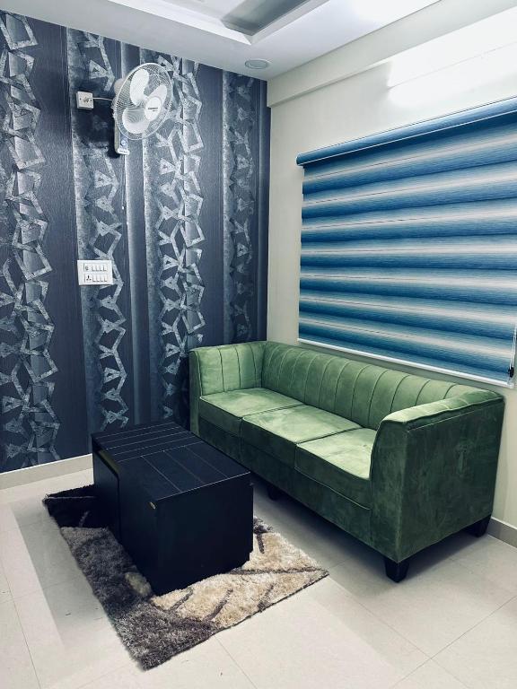 un sofá verde sentado en una habitación con una pared en ADDRESS service apartment, en Bangalore
