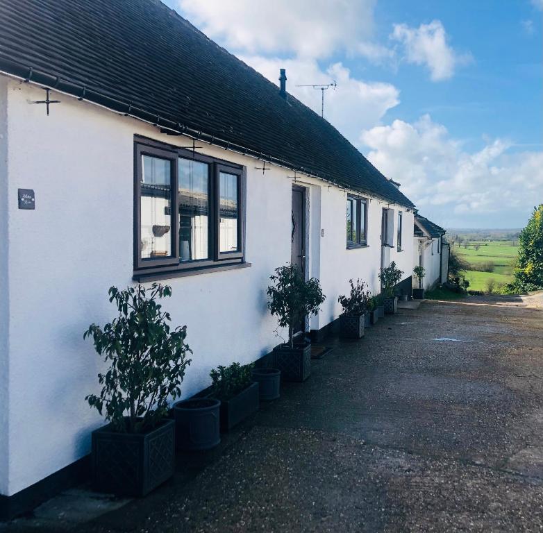 a white house with potted plants in front of it at Little Park Holiday Homes Self Catering Cottages 1 & 2 bedrooms available close to Tutbury Castle in Tutbury