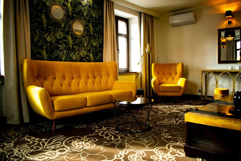 a living room with a yellow couch and two chairs at Hotel Pruski in Orneta