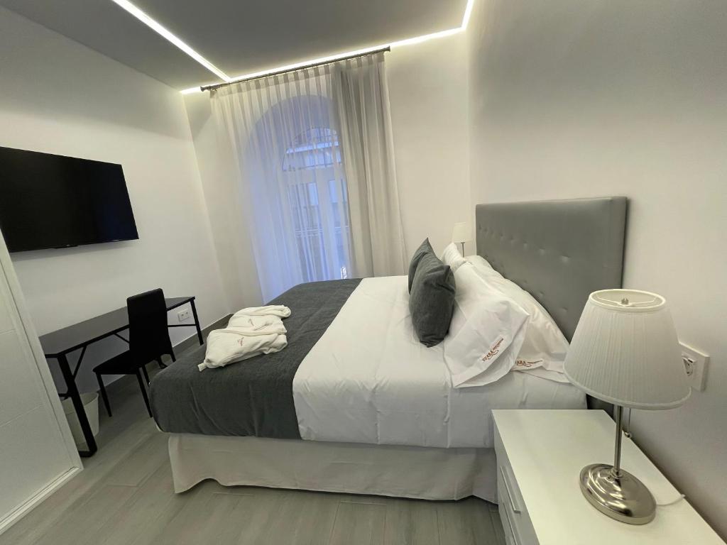 a bedroom with a bed and a desk with a lamp at SUARA Apartamentos 1 in Madrid