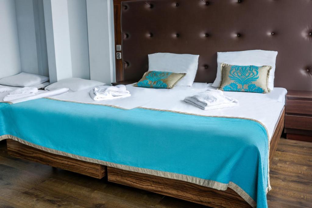 a large bed with blue and white sheets and pillows at Hotel Opera in Tarnowskie Góry