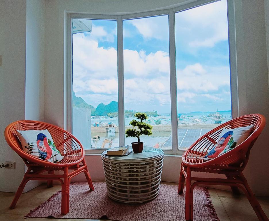 duas cadeiras e uma mesa em frente a uma janela em SG Tourist Inn em El Nido