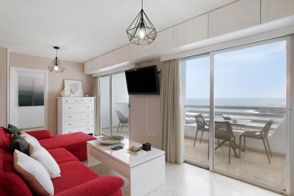 a living room with a red couch and a view of the ocean at Apartamentos Tamara in Tacoronte