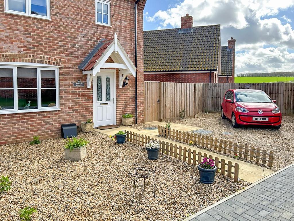 a red car parked in front of a brick house at Lapwing Lodge in New Hunstanton